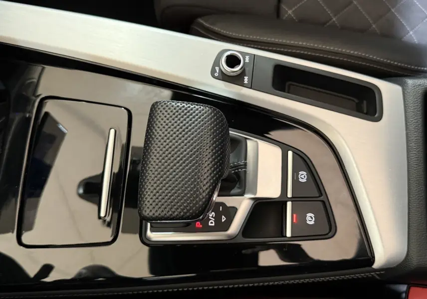 Gros plan sur la console centrale noire et argentée de l'Audi A4 35 TFSI avec levier de vitesse et commandes électroniques.