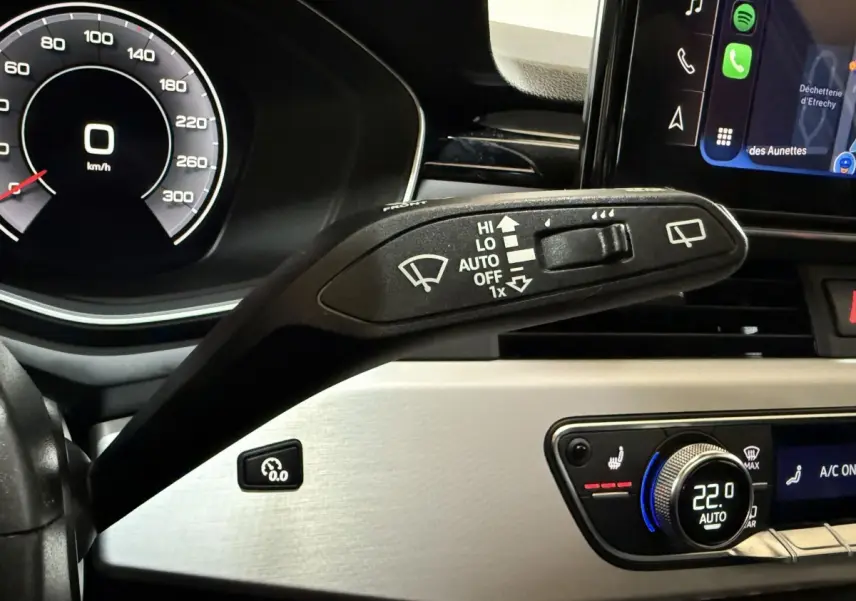 Gros plan sur la commande d’essuie-glace à gauche du volant dans l’habitacle de l’Audi A4 gris foncé, avec tableau de bord digital.