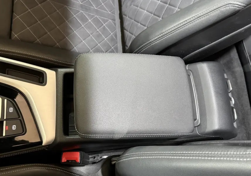 Vue en plongée du couvercle de la console centrale en cuir noir avec surpiqûres blanches de l'Audi A4 gris foncé.