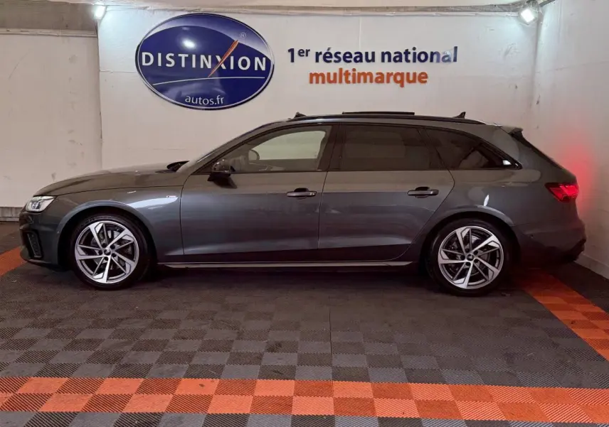 Vue latérale gauche d'une Audi A4 35 TFSI S Edition gris foncé en break, stationnée en intérieur sur sol à damiers.
