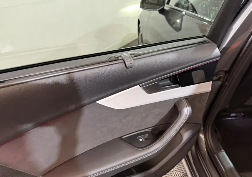 Intérieur de la porte arrière droite d’une Audi A4 gris foncé, avec garniture cuir et inserts aluminium.