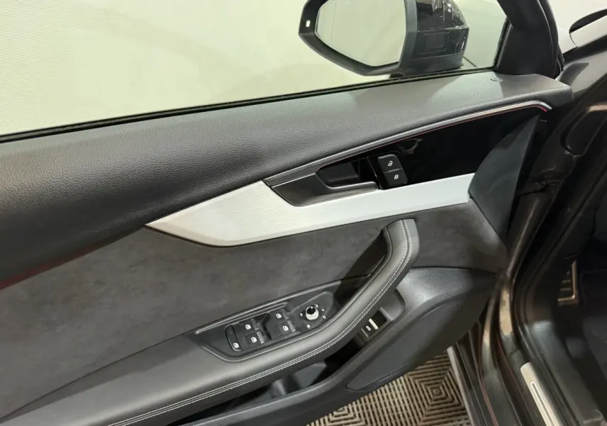 Vue intérieure côté conducteur de la porte gris foncé de l'Audi A4 35 TFSI avec commandes électriques et garniture cuir et alcantara.