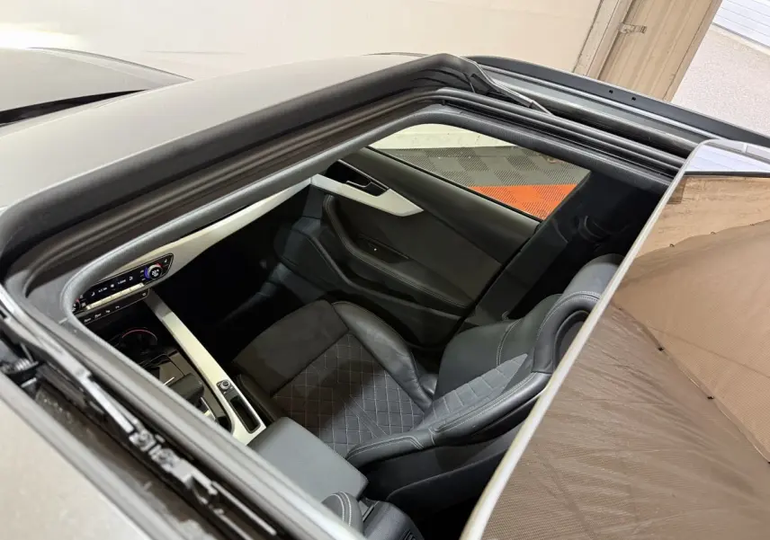 Vue plongeante par le toit ouvrant sur l'intérieur noir et gris de l'Audi A4 35 TFSI S Edition 2022.
