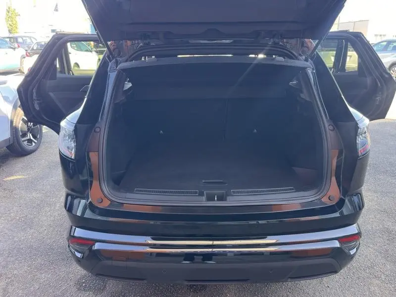 Vue arrière du coffre ouvert d'un Renault Austral noir étoilé avec portes arrière ouvertes, en extérieur.
