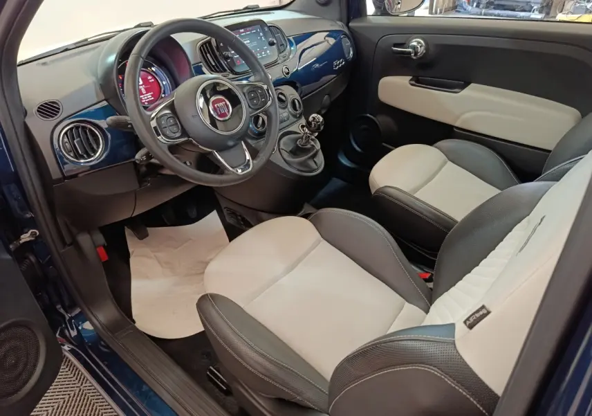Vue intérieure côté conducteur de la Fiat 500 Dolcevita 2022, tableau de bord bleu et sièges bicolores cuir noir et beige.