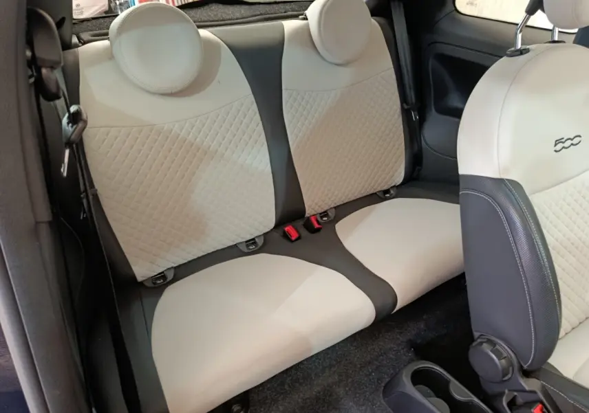 Vue intérieure sur la banquette arrière beige et noire de la FIAT 500 Hybrid 2022 avec appuie-têtes ronds.