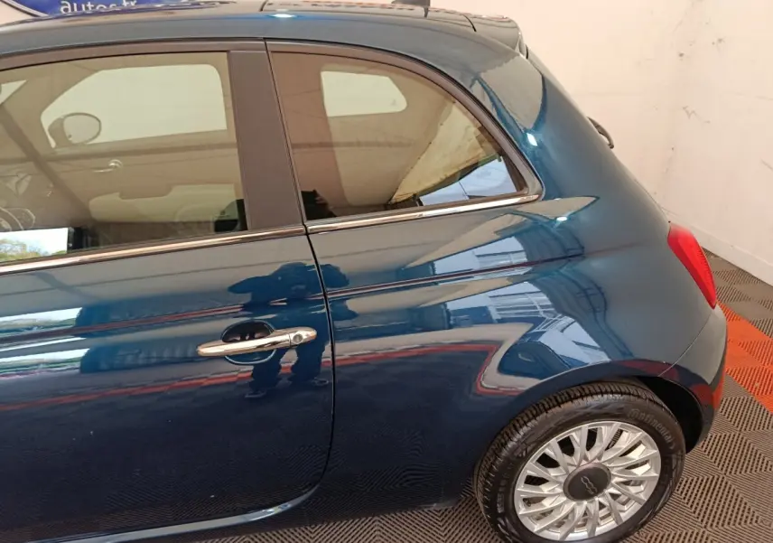 Vue latérale côté droit d'une FIAT 500 Hybrid bleu métallisé avec jante alliage et poignée chromée.