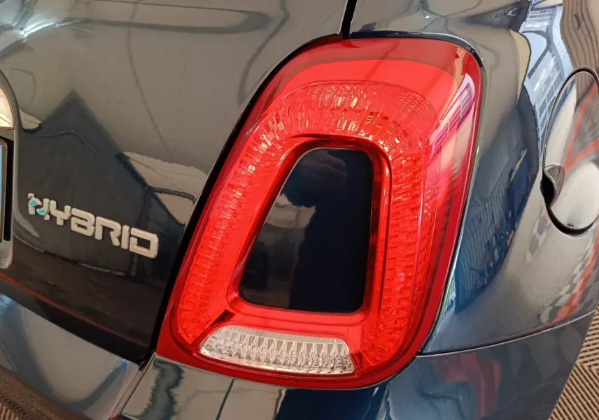 Gros plan sur le feu arrière droit rouge et le logo Hybrid sur la carrosserie bleue d'une Fiat 500.