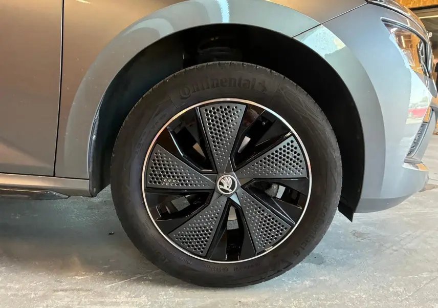 Gros plan sur la roue avant gauche d’un Skoda Kamiq gris foncé 2024 avec jante noire et grise au design moderne.