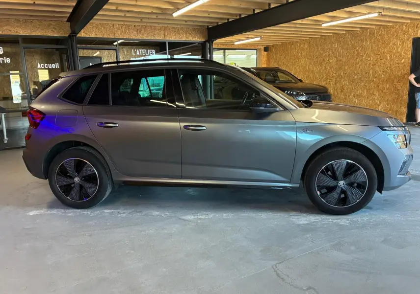 Vue de profil côté gauche d'un Skoda Kamiq gris foncé 2024 finition Monte-Carlo avec jantes noires distinctives.