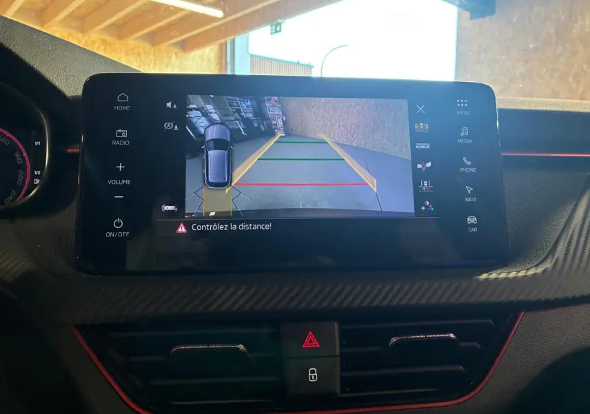 Écran central du Skoda Kamiq 2024 montrant la caméra de recul avec guidage de trajectoire, tableau de bord noir.