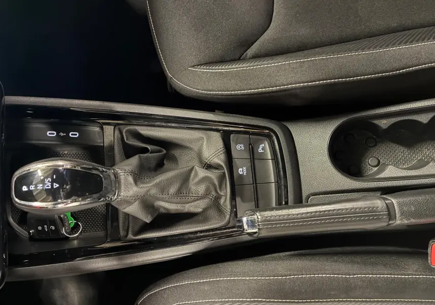 Vue plongeante sur la console centrale noire du Skoda Kamiq 2024, avec levier de vitesse automatique et frein à main cuir.