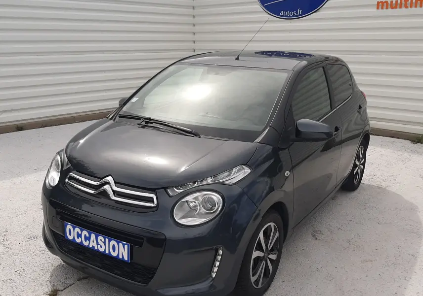 Citroën C1 gris foncé vue 3/4 avant droit, compacte 5 portes avec jantes bi-ton et feux LED diurnes.