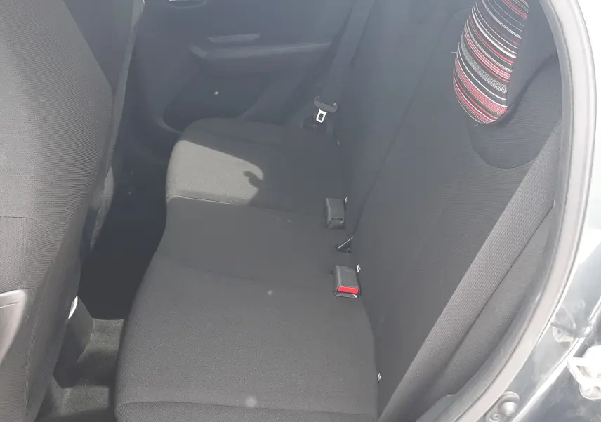Vue intérieure côté droit sur la banquette arrière noire avec appuie-têtes rayés d'une Citroën C1 gris foncé 2019.