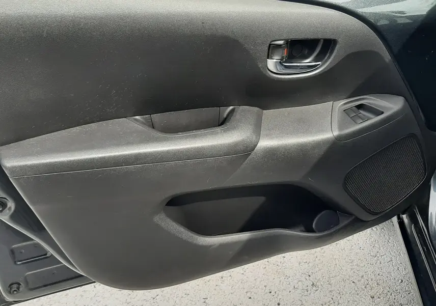 Vue rapprochée de la porte avant droite de la Citroën C1 gris foncé, montrant la poignée intérieure et les commandes de fenêtre.