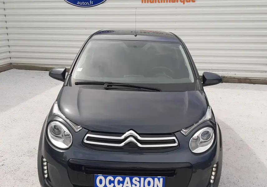 Vue avant d'une Citroën C1 gris foncé 2019 avec phares ronds et logo double chevron bien visible.