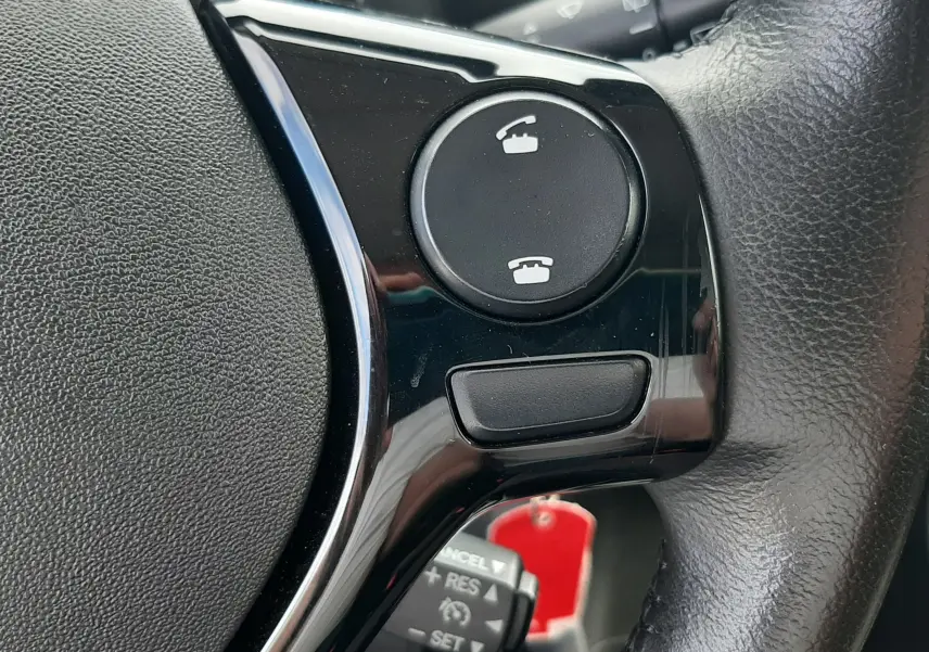 Gros plan sur les commandes téléphoniques et régulateur au volant noir de la Citroën C1 VTi 72CH Shine 2019.