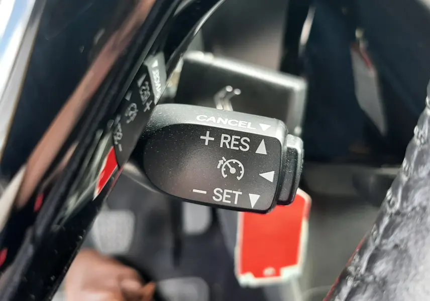 Gros plan sur la commande de régulateur de vitesse dans l'habitacle d'une Citroën C1 gris foncé, version Shine 2019.