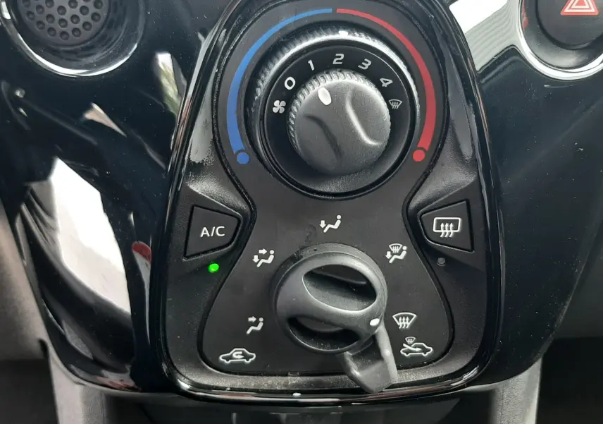 Vue rapprochée du tableau de commande de climatisation noir brillant d'une Citroën C1 gris foncé de 2019.