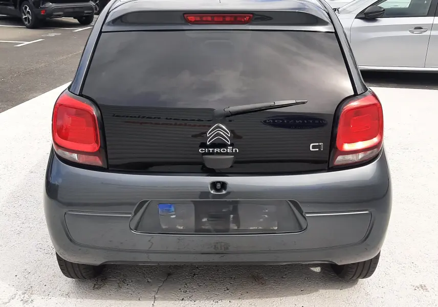 Vue arrière d'une Citroën C1 gris foncé 2019 avec vitres teintées et feux arrière rouges visibles.