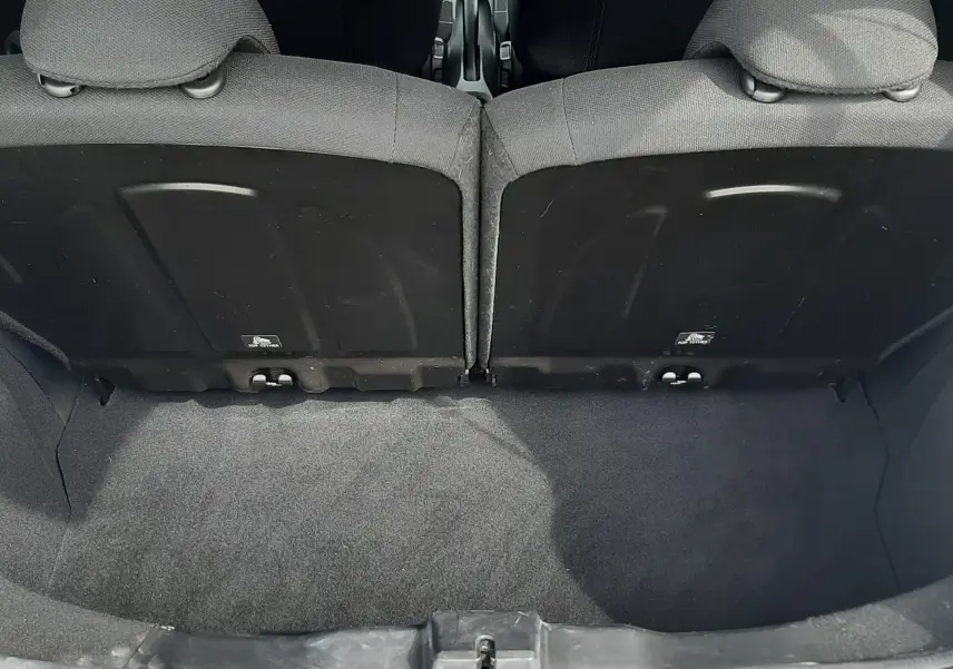 Vue depuis le coffre ouvert d'une Citroën C1 gris foncé 2019, montrant l'intérieur noir et les dossiers arrière des sièges.