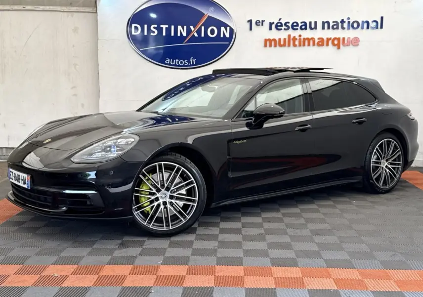 Vue 3/4 avant droite d'une Porsche Panamera 4 E-Hybrid Sport Turismo noire avec jantes alliage et logo "e-hybrid" sur la porte.