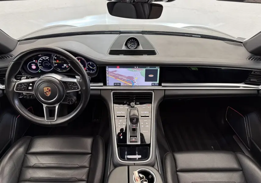 Vue intérieure avant de la Porsche Panamera 4 E-Hybrid Sport Turismo 2018, tableau de bord noir avec écran tactile navigation.