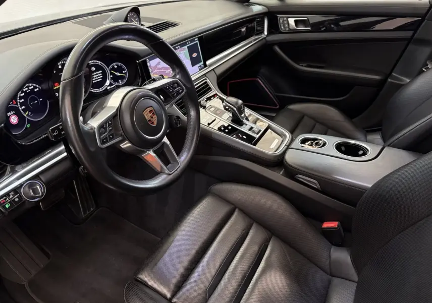 Intérieur noir de la Porsche Panamera 4 E-Hybrid Sport Turismo 2018, vue côté conducteur avec volant cuir multifonctions et écran tactile.