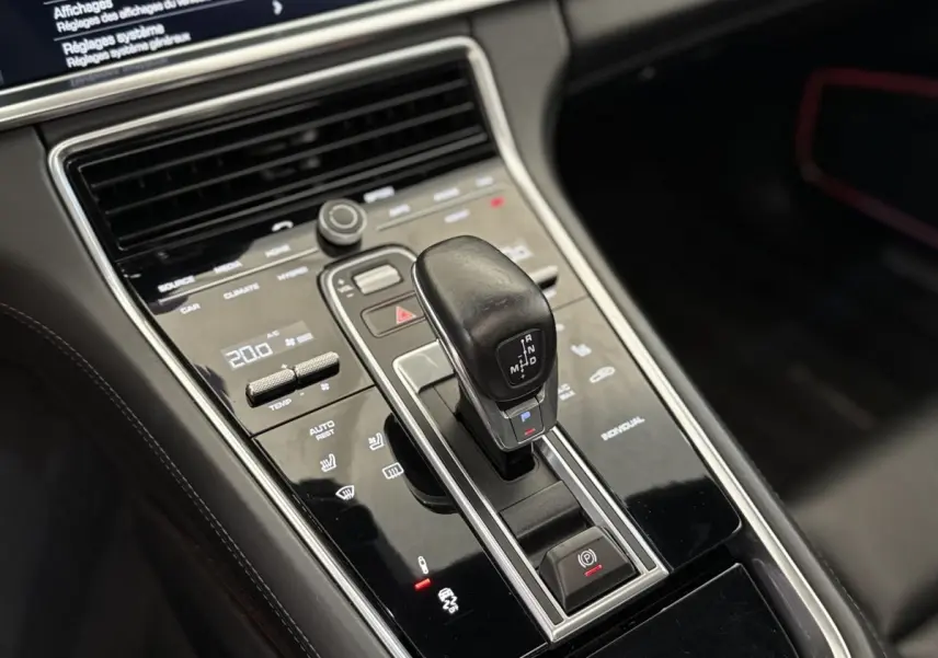 Gros plan sur la console centrale noire de la Porsche Panamera 4 E-Hybrid Sport Turismo avec levier de vitesse et commandes tactiles.