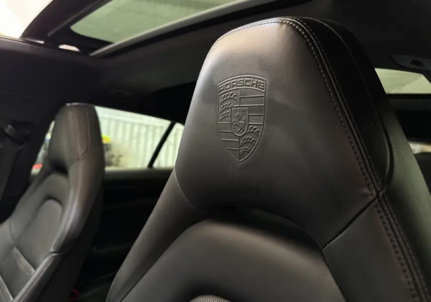 Gros plan sur l'appui-tête en cuir noir embossé du logo Porsche à l'avant intérieur d'une Panamera 4 E-Hybrid Sport Turismo.