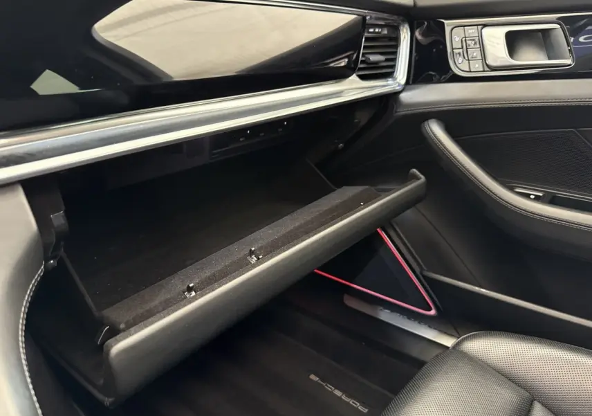 Vue intérieure côté passager de la Porsche Panamera 4 E-Hybrid Sport Turismo 2018, boîte à gants ouverte, garnitures noires élégantes.