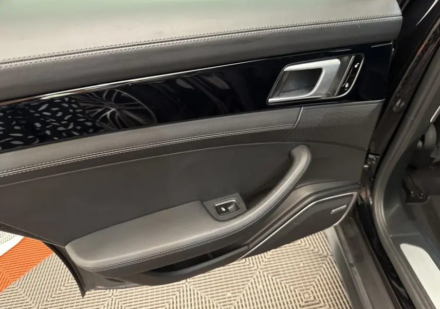 Vue intérieure de la porte avant gauche noire de la Porsche Panamera 4 E-Hybrid Sport Turismo avec garniture cuir et poignée argentée.