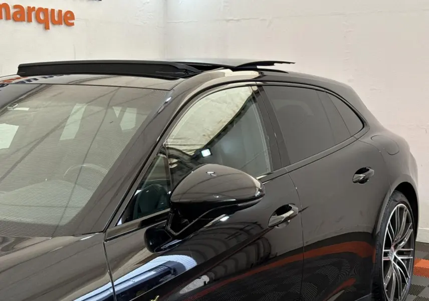 Vue de côté droit avant d'une Porsche Panamera 4 E-Hybrid Sport Turismo noire avec rétroviseur et jante alliage visibles.