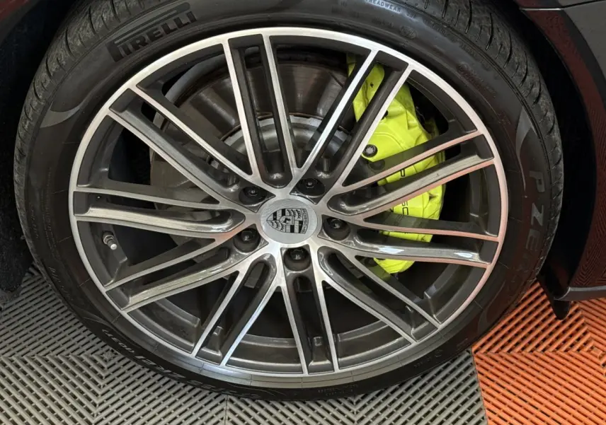 Gros plan sur la jante alliage de la Porsche Panamera 4 E-Hybrid Sport Turismo noire avec étrier de frein jaune vif.