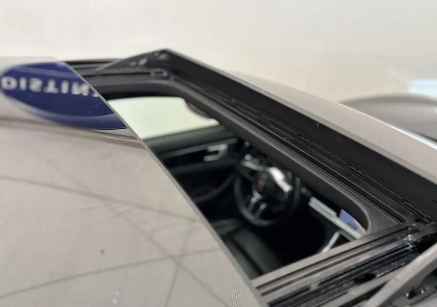 Vue rapprochée du toit ouvrant ouvert d’une Porsche Panamera 4 E-Hybrid Sport Turismo noire, intérieur cuir visible.