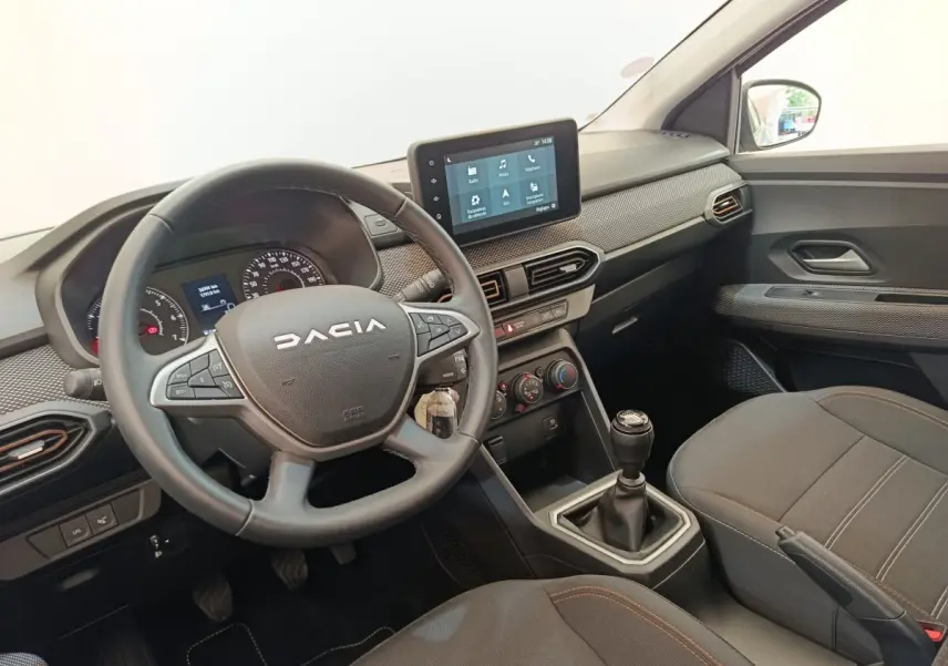 Vue intérieure côté conducteur de la Dacia Sandero Expression EGO-G 100 2023, volant cuir, écran tactile 8 pouces et boîte manuelle.