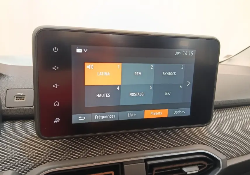 Écran tactile central du tableau de bord de la Dacia Sandero gris clair, affichant les stations radio en mode presets.
