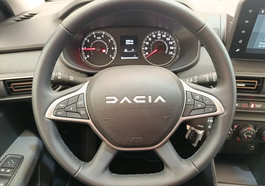 Vue rapprochée du volant cuir multifonctions noir de la Dacia Sandero 2023 avec tableau de bord et écran tactile visibles.
