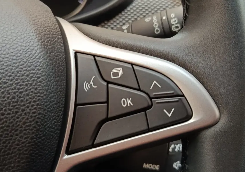 Gros plan sur les commandes multifonctions du volant cuir synthétique de la Dacia Sandero gris clair 2023.