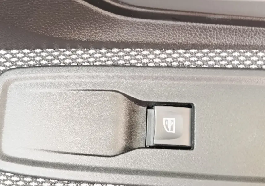 Gros plan sur l'interrupteur de lève-vitre côté porte intérieure d'une Dacia Sandero gris clair 2023.