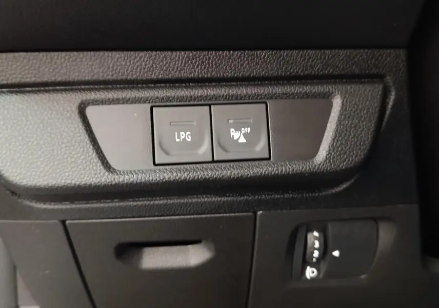 Gros plan sur les boutons LPG et désactivation capteurs de stationnement dans l'habitacle noir du Dacia Sandero gris clair.