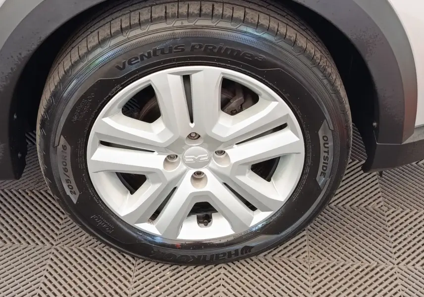 Gros plan sur la roue avant droite d'une Dacia Sandero gris clair, mettant en valeur la jante et le pneu Hankook.