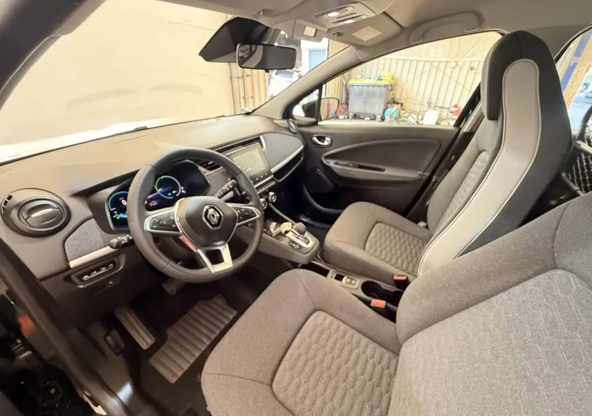 Vue intérieure côté conducteur de la Renault ZOE noire 2024, volant cuir multifonctions et tableau de bord digital.