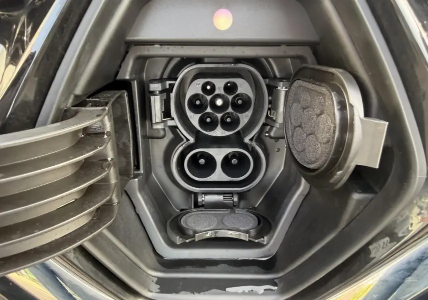 Prise de charge électrique ouverte sur Renault ZOE noire, vue rapprochée du port de recharge côté avant droit.