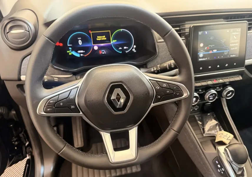 Vue intérieure centrée sur le volant cuir noir et le tableau de bord digital de la Renault ZOE 2024 électrique.