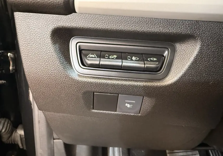 Gros plan sur les commandes noires situées sous le tableau de bord côté conducteur de la Renault ZOE noire 2024.