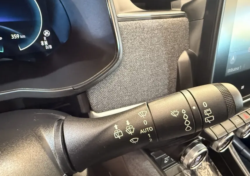 Gros plan sur la commande des essuie-glaces dans l'habitacle de la Renault ZOE noire, avec tableau de bord numérique visible.
