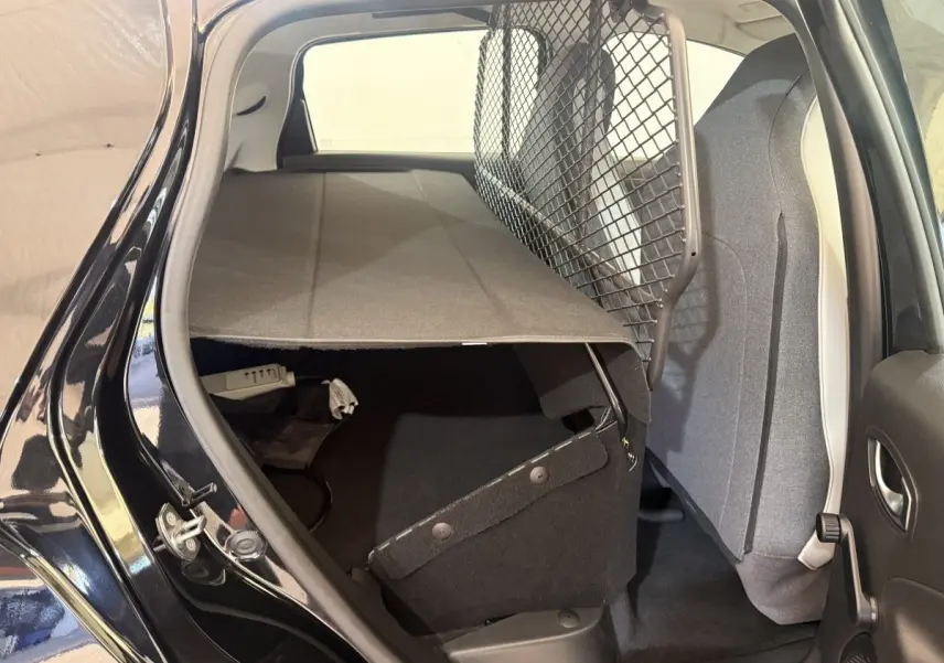 Vue intérieure arrière côté droit de la Renault ZOE noire 2024 avec séparation grillagée et banquette rabattue.