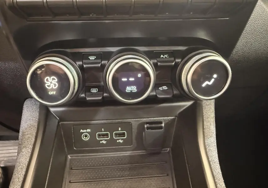 Gros plan sur la console centrale de la Renault ZOE noire, montrant les commandes de climatisation et ports USB.