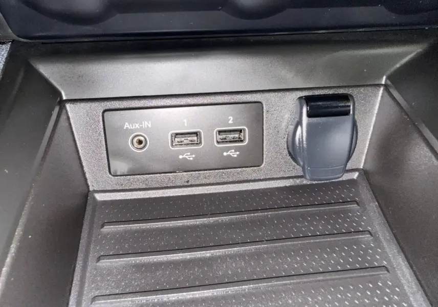Gros plan sur les prises USB, Aux-IN et prise 12V dans le rangement avant de la Renault ZOE noire 2024.